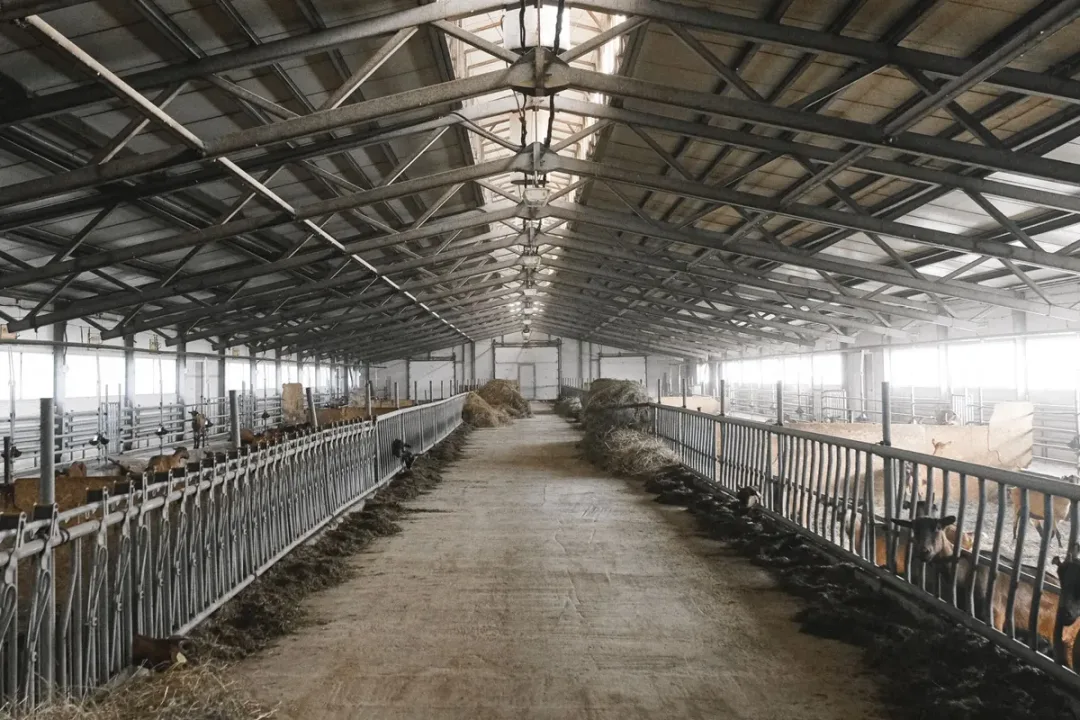 Open interior of a pole barn showing wide-span metal roof trusses used for storage