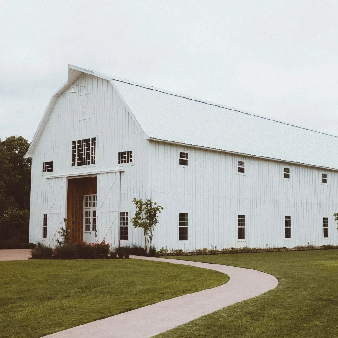 Large white pole barn with a metal roof and covered entryway on a landscaped North Florida property