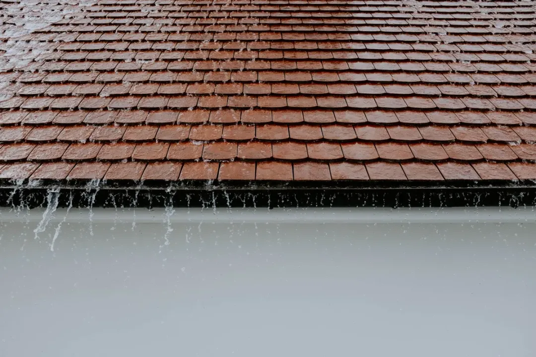 Rain cascading off a shingle roof and into the gutter during a North Florida summer storm