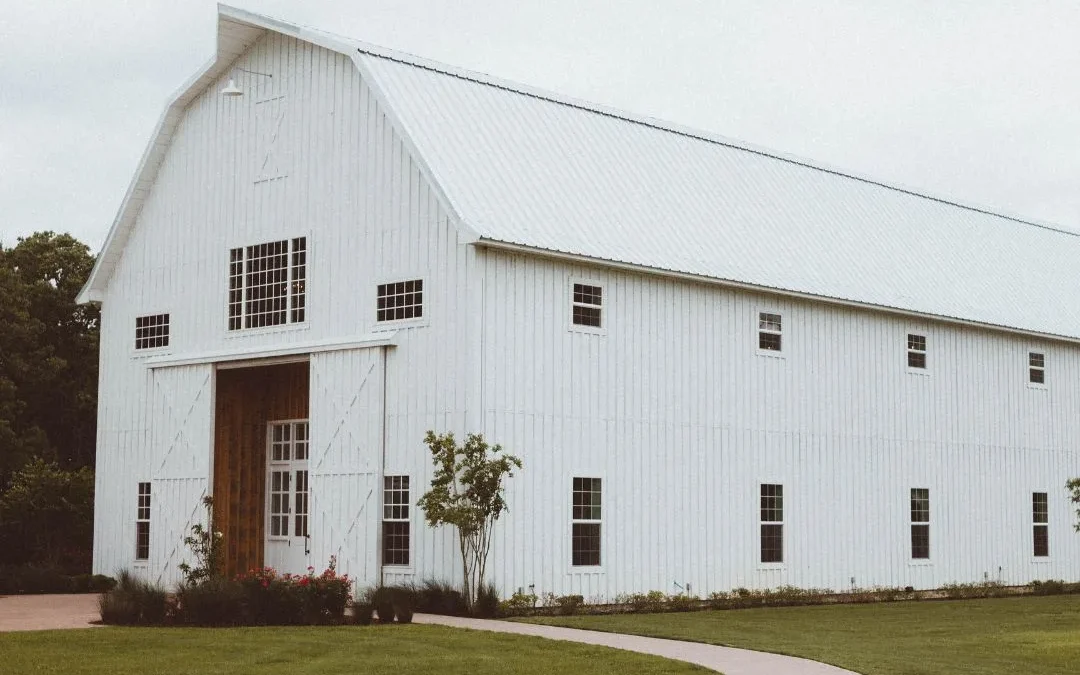 Large white pole barn with a metal roof and covered entryway on a landscaped North Florida property